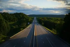 Longue autoroute à plusieurs voies traversant un paysage verdoyant ; convoyage de véhicules longue distance par KirriGo.