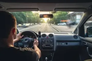 Un convoyeur automobile KirriGo au volant, vue de l'intérieur, sur une route ensoleillée